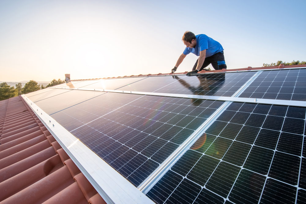 En person installerar solceller på ett tak