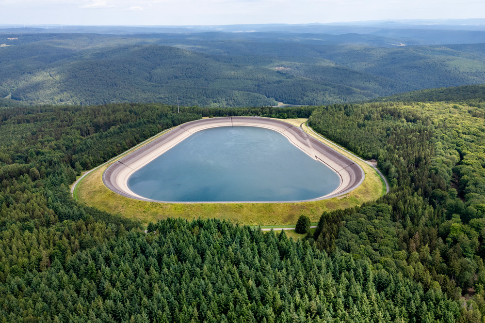 pumped-storage hydroelectric power plant surrounded by dense forest and rolling hills.