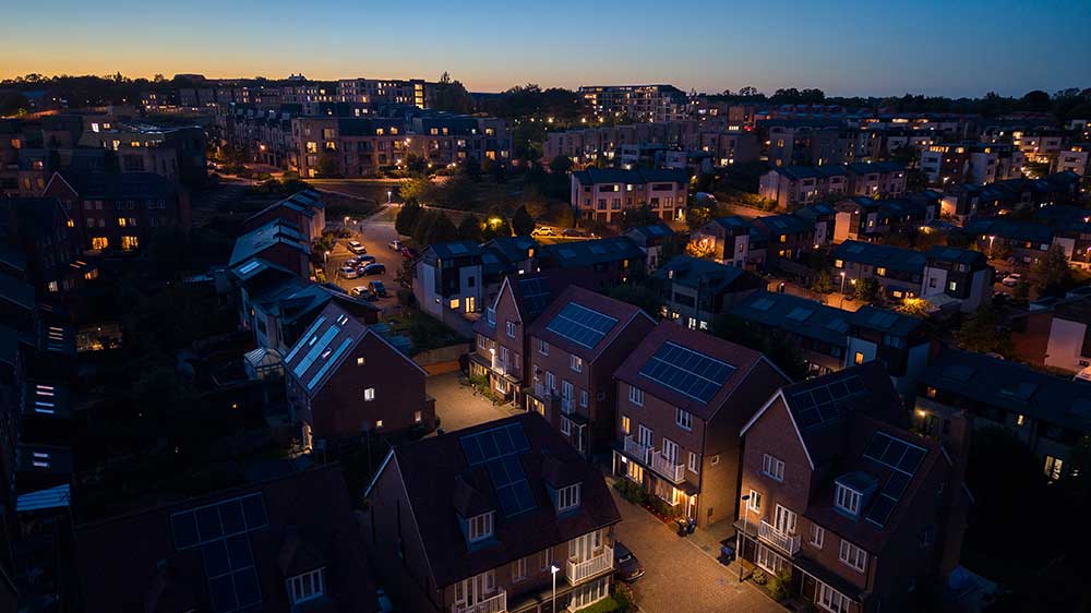 Modernt bostadsområde i skymningen där parhus med solpaneler på taken