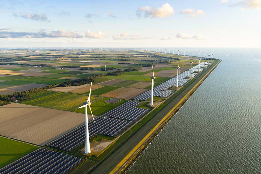 Flygfoto över Noordoostpolder med vindkraftverk och solpanelsfält längs kusten i Friesland, Nederländerna