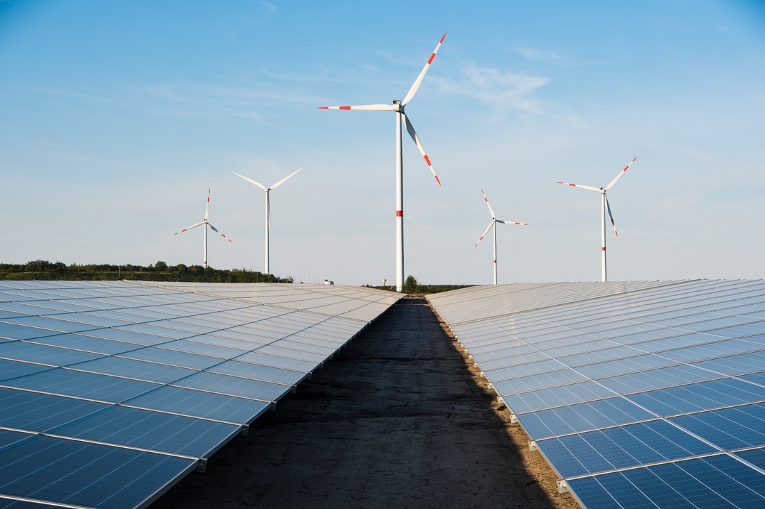 Solarpaneler som leder upp till ett vindkraftverk